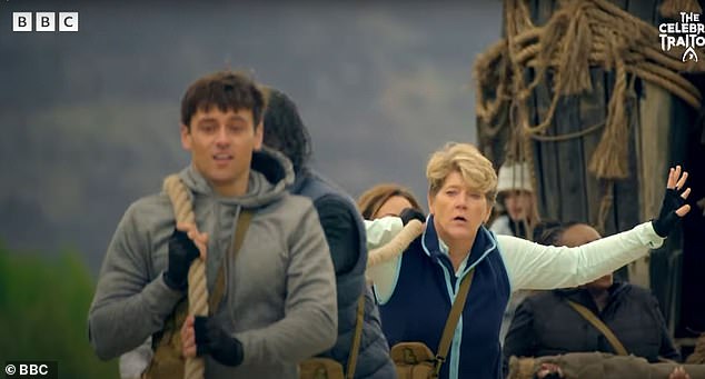 One appears to involve the stars being tasked with dragging a large wooden structure on wheels, as Claudia yells encouragement at them from the sidelines