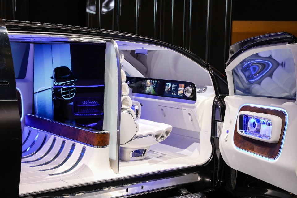 Interior of the Mercedes-Benz Vision V electric concept vehicle with white seats, blue accent lighting, and a screen in the dashboard, displayed at the Auto Shanghai 2025.