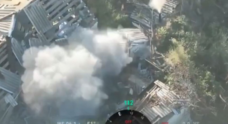 Aerial view showing smoke after a strike on a destroyed building, with a targeting reticle in the center.