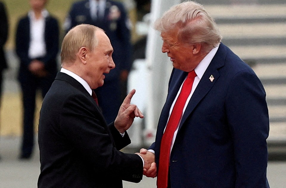 Russian President Vladimir Putin shakes hands with U.S. President Donald Trump while pointing a finger at him.