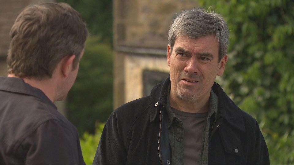 Cain Dingle looking worried as DC Cole talks about Nate's murder investigation.