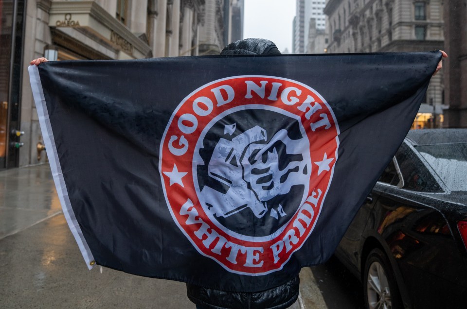 A person holding a black "Good Night White Pride" Antifa flag.