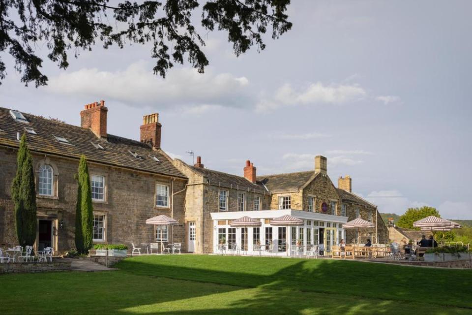 The Cavendish Hotel in Baslow with outdoor seating areas and a green lawn.