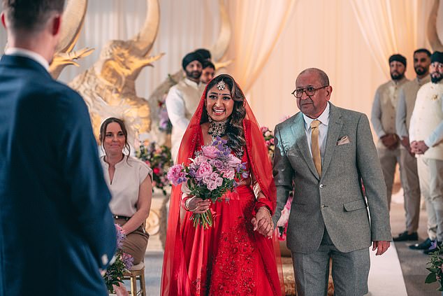 Nelly, pictured walking down the aisle with her father, opted for a traditional Indian-style wedding dress, in a beautifully deep, crimson red with matching veil