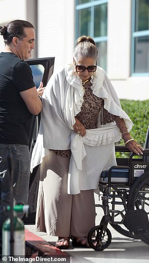 A male companion is seen helping her out of the car and into her wheelchair