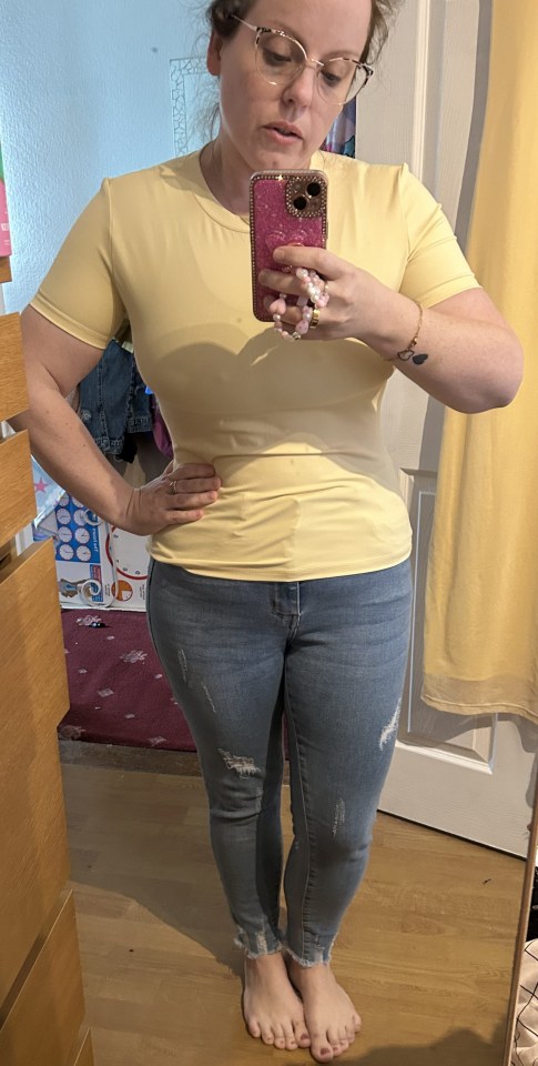 Person taking a mirror selfie wearing a yellow shirt and distressed jeans.