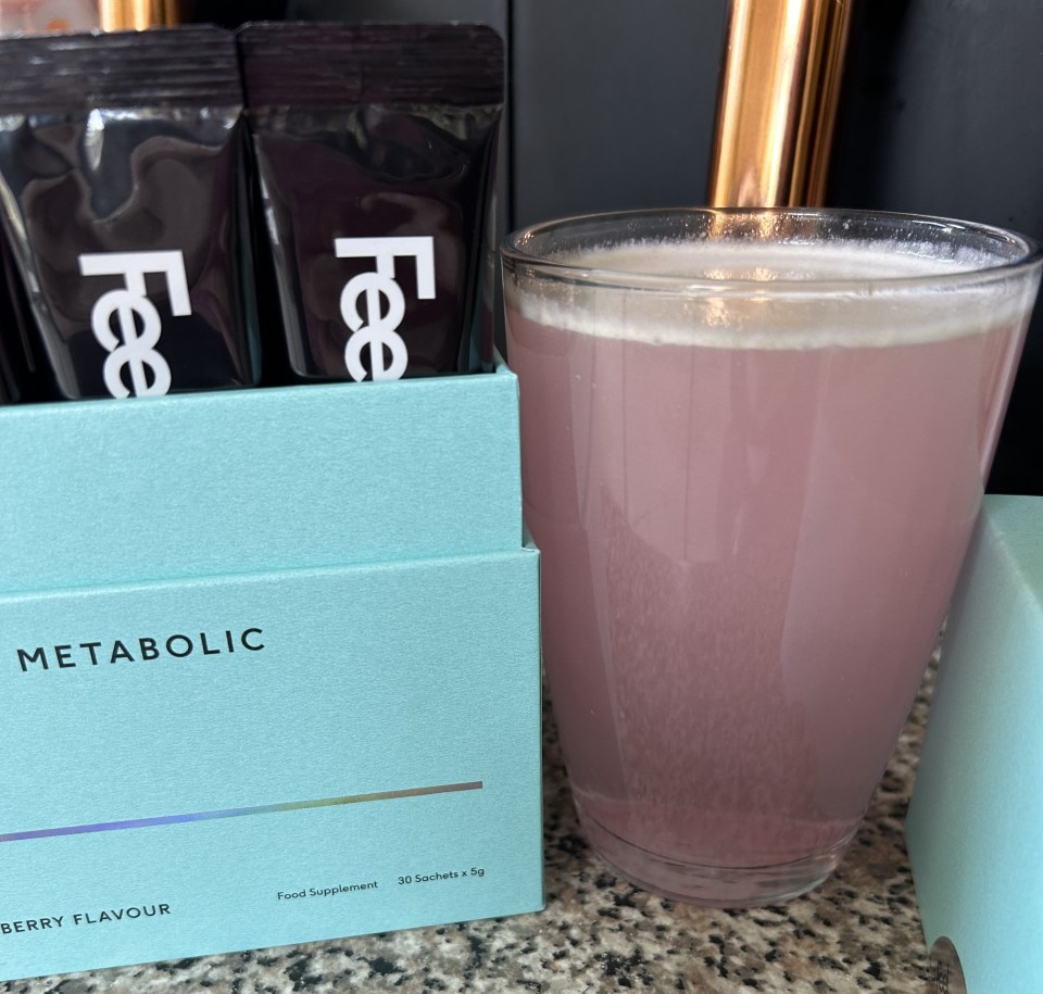 Berry-flavored metabolic supplement sachets and a glass of the mixed drink.