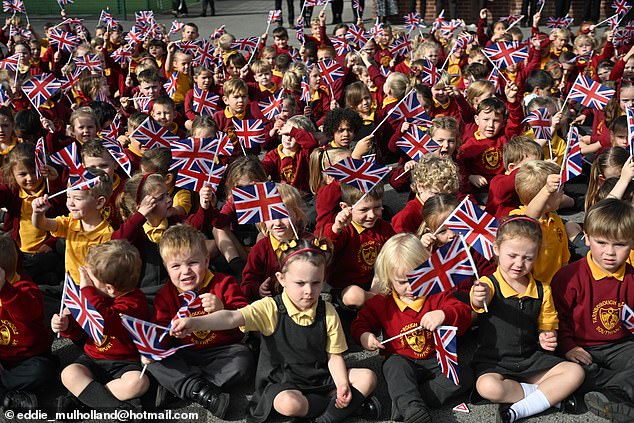 Pupils at Farnborough Road Infant and Junior School wave Union Jacks while waiting for the future King and Queen