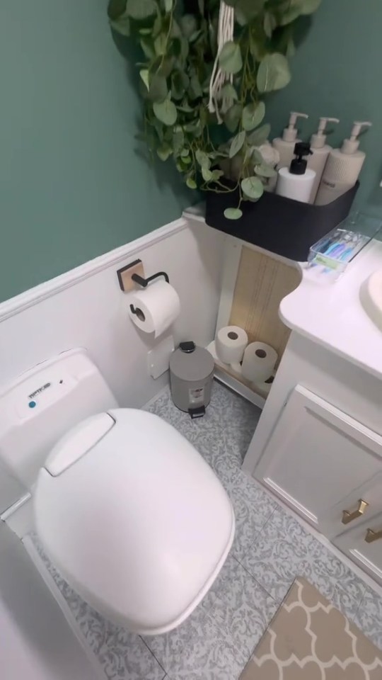 A small, refurbished caravan bathroom with a white toilet, gray patterned floor, and teal accent wall.