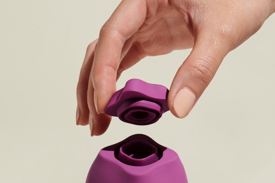 A hand holding the removable top of a purple sex toy.