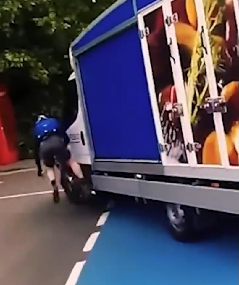A cyclist on the ground next to a bicycle after being hit by a white delivery van.