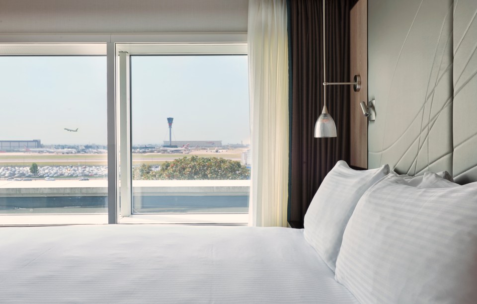 A king-size bed in a hotel room with an airport runway visible through the window.