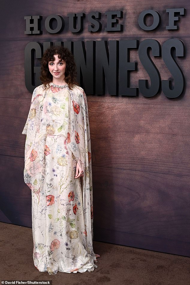Emily cut an ethereal figure in a flowing chiffon cape dress decorated in a colourful pattern of wildflowers and boasting a diamond-studded collar