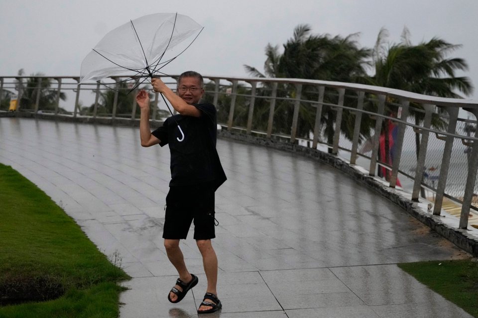 A man struggles to hold onto his umbrella in strong winds.