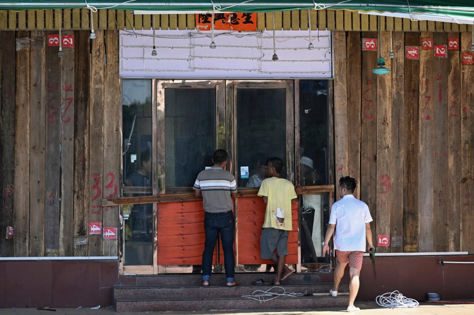 People install wood panels on a restaurant to resist wind ahead of an approaching typhoon.