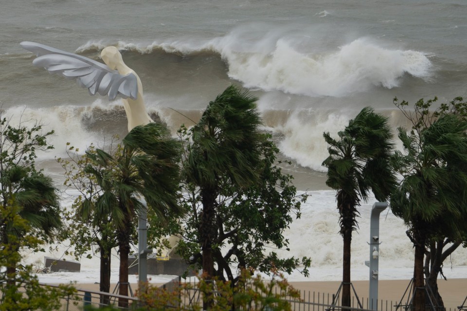 Waves crash onto a beach near a giant winged sculpture in Shenzhen.