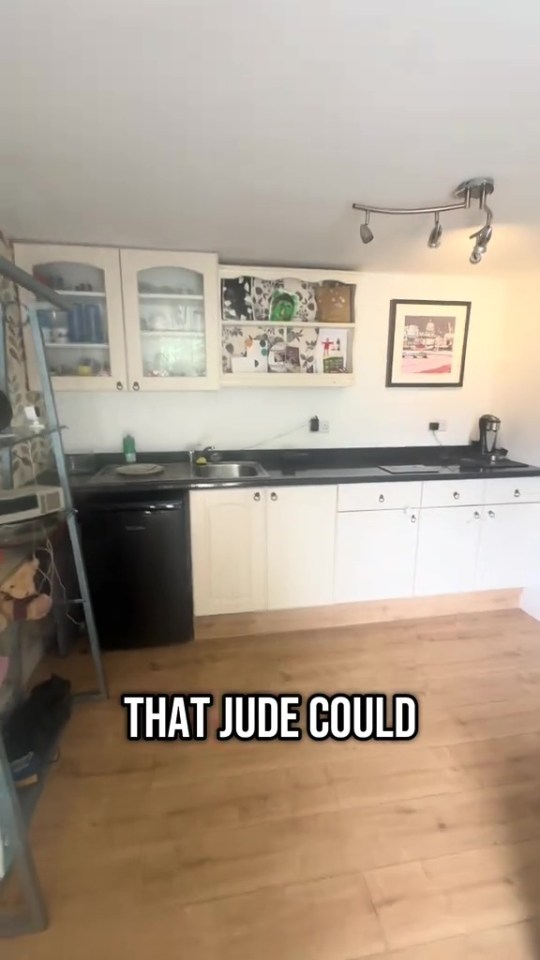 Kitchenette with white cabinets and light wood floors.
