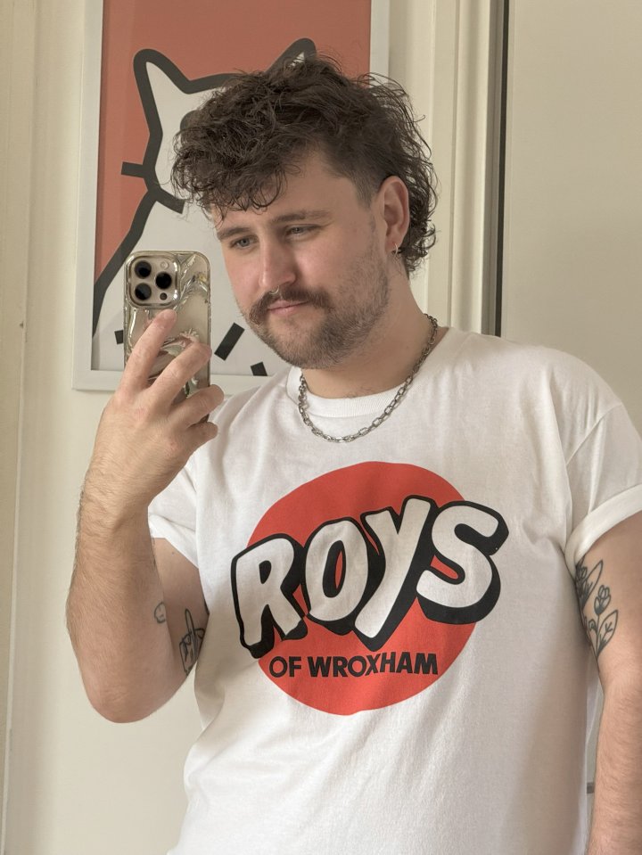 Gareth Clarke taking a selfie while wearing a "Roys of Wroxham" t-shirt.