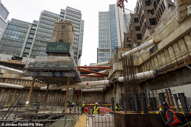 The historic church tower is seen on stilts above the construction site