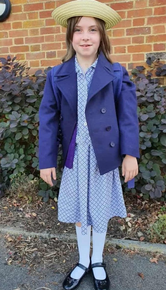 Sienna in her school uniform, wearing a blue jacket, patterned dress, and straw hat.