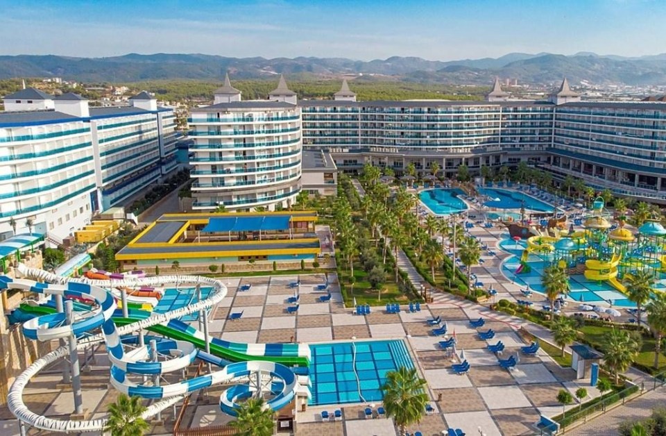 The Eftalia Ocean Hotel in Antalya, Turkey with multiple pools, waterslides, and a view of mountains in the background.