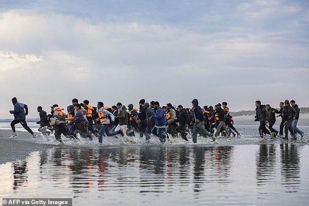 Migrants sprint across a beach at Gravelines, northern France, in August to reach a people trafficker dinghy just off the shore