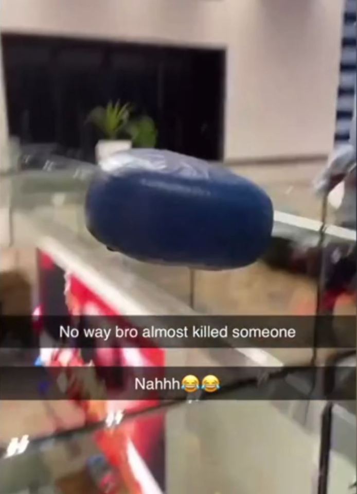 A large blue beanbag-like seat being thrown over a railing in a shopping center.