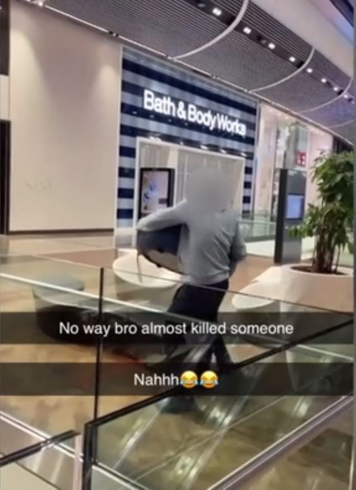 A person carrying a seat, about to throw it off a shopping centre balcony.