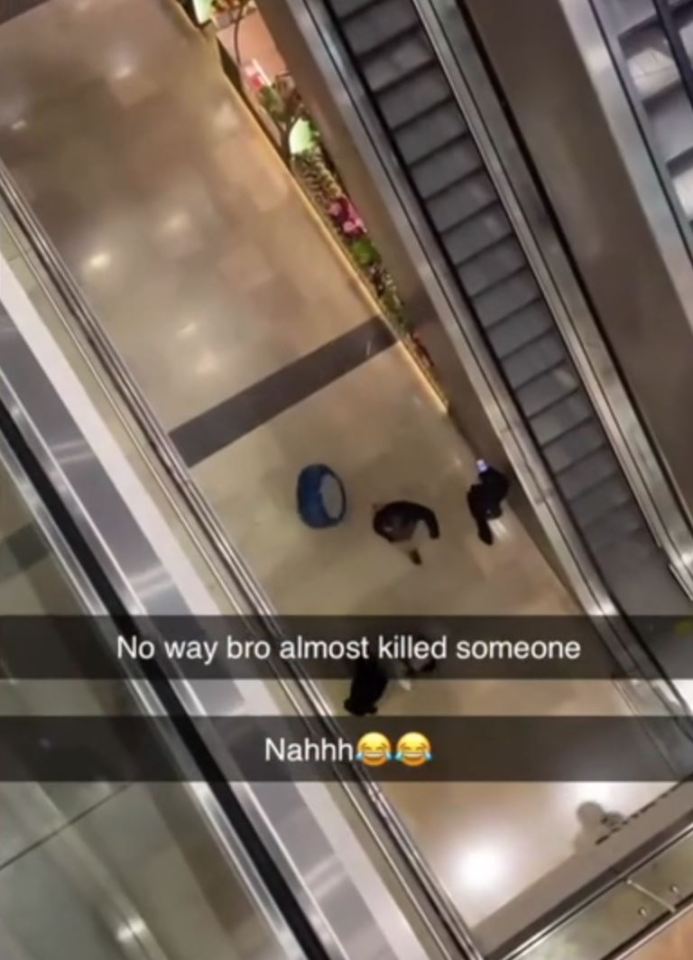 An aerial shot of a shopping center floor showing two people near a blue seat, with escalators on either side. Text overlaid on the image says "No way bro almost killed someone" and "Nahhh".
