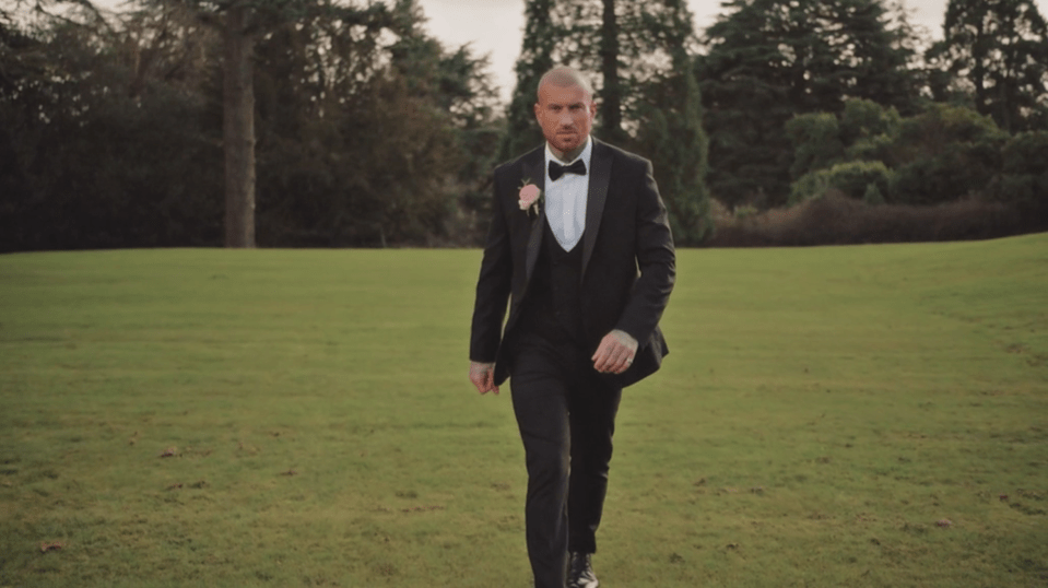 A groom walking on a grassy field, looking forward.