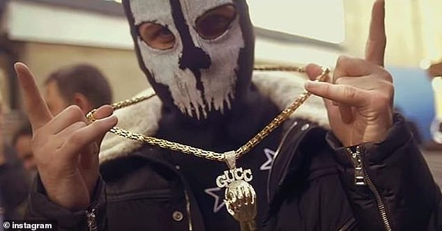 A Hellbanianz gang member poses masked with a gold medallion. The Hellbanianz ran a public Instagram page flaunting their gangster lifestyle until it was taken off the social media platform