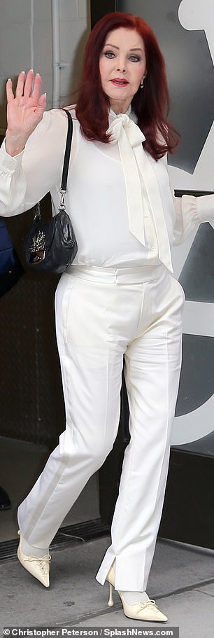 The star was a vision in a semi-sheer white pussy bow blouse, matching trousers, and dainty heels