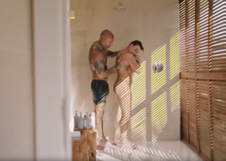 Two men showering together, with one man washing the other's back.