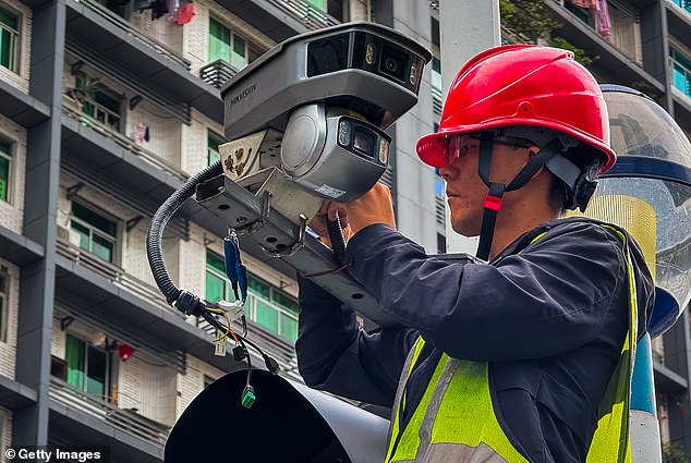 A worker installs a surveillance camera on a city street on October 22, 2024 in Chongqing, China