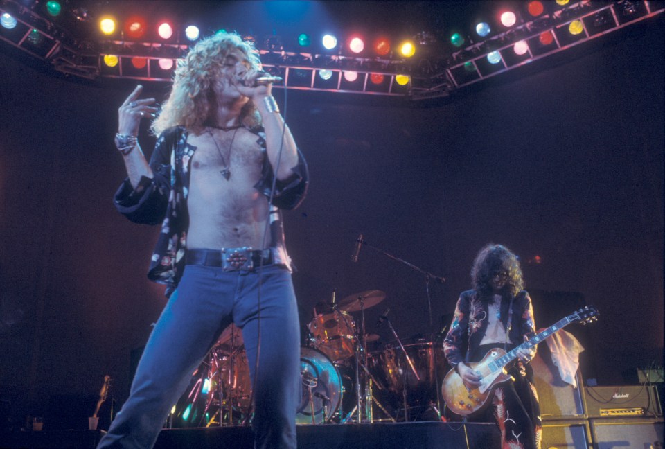 Robert Plant and Jimmy Page performing on stage with colorful stage lights above.