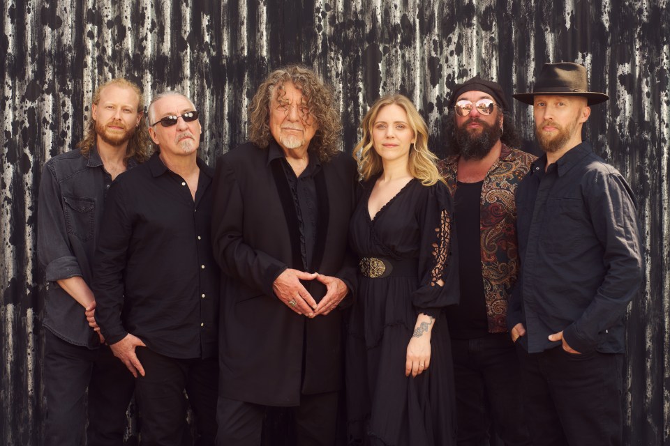Robert Plant and his band Saving Grace standing against a corrugated metal backdrop.