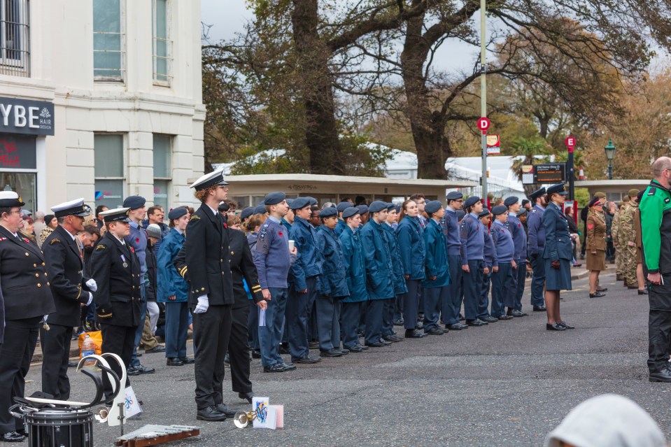 A group of military personnel and cadets standing in formation at a remembrance ceremony.