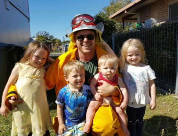 A firefighter posing with four young children.