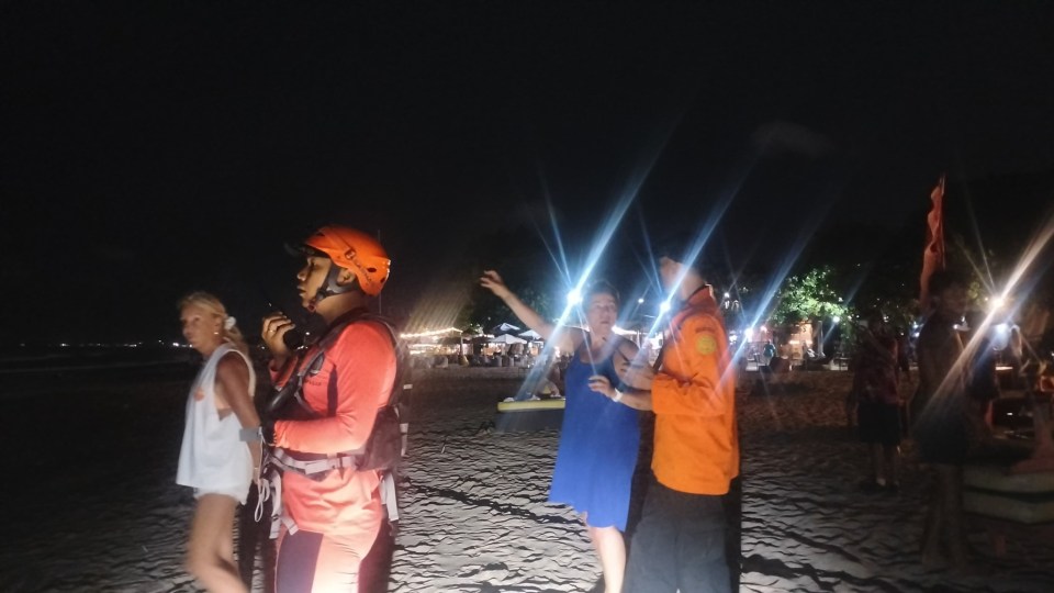 Rescue teams searching for a British tourist on Legian Beach, Bali at night.