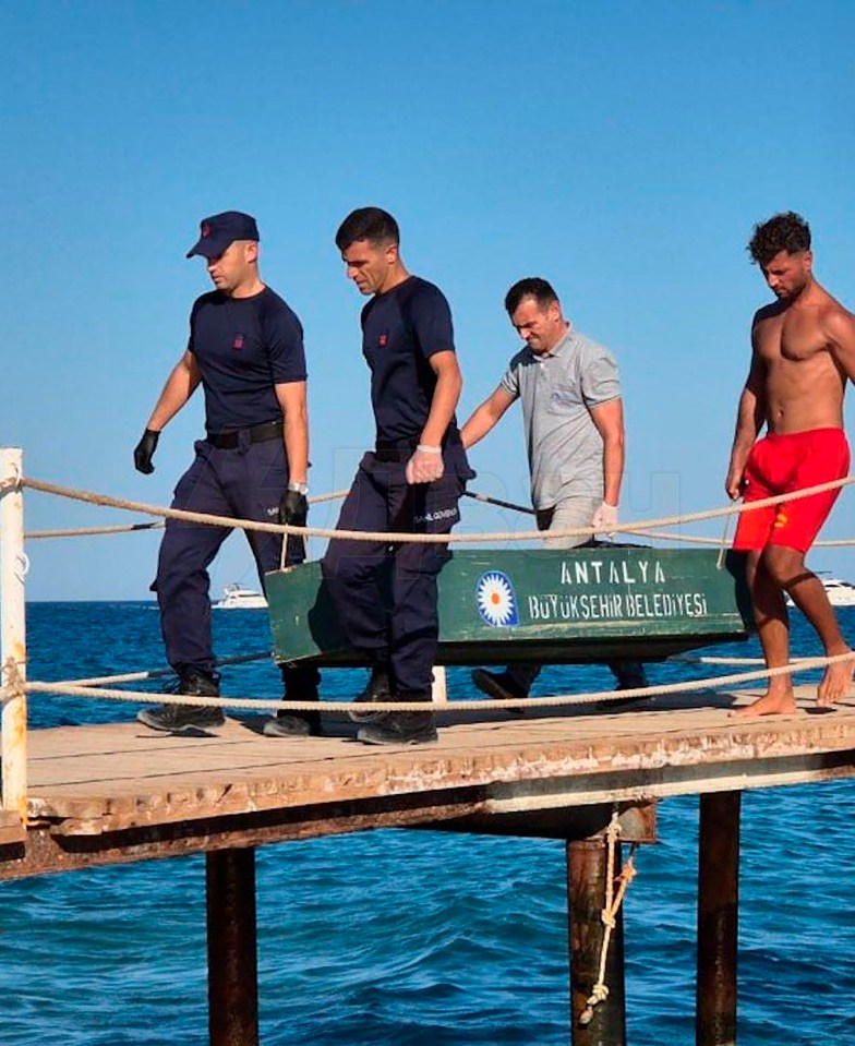 Four men carrying the body of Linariya Muzipova, 42, on a stretcher off a wooden pier in Kemer, Turkey.