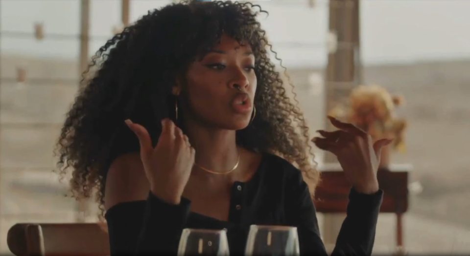 Woman with curly hair in a black top talking with her hands.