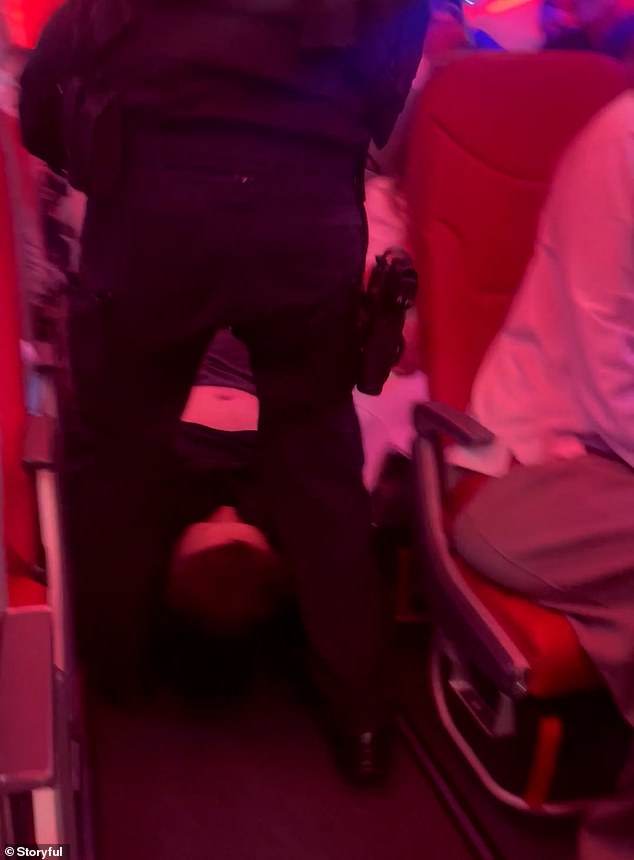 Two cops were filmed carrying the passenger by his arms and legs down the middle of the plane aisle
