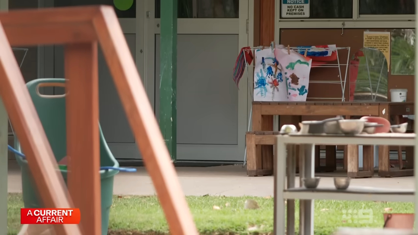 Children's artwork drying on a clothes rack outside a building.