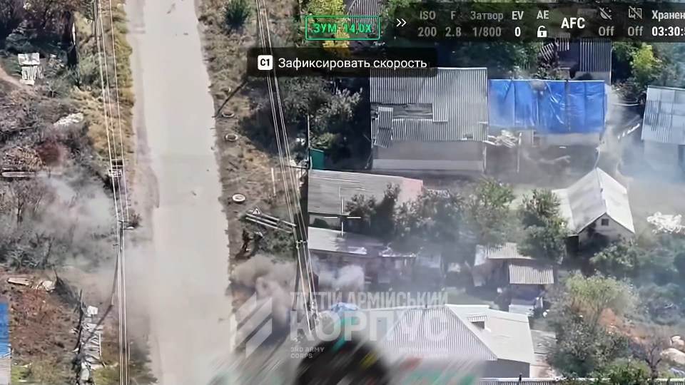 Aerial view of a Ukrainian village with smoke visible near houses and a road, showing Russian forces taking a girl hostage.