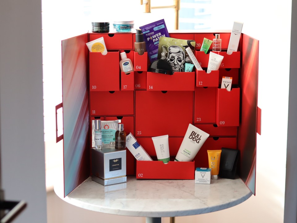 A red advent calendar for beauty products and cosmetics with various products on its shelves.