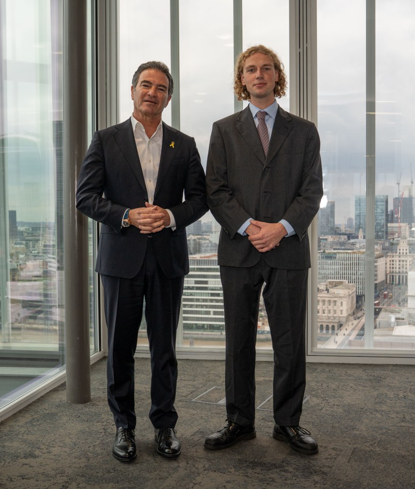 Yossi Cohen, former head of Mossad, and Sun reporter Patrick Harrington standing in front of a window with a city skyline view.