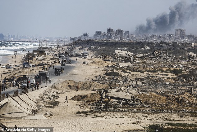 Smoke rises from ongoing strikes as Palestinians, carrying their belongings by vehicle or on their backs, continue to flee toward southern Gaza via al-Rashid Street after intensified Israeli attacks and ground operation amid forced evacuation orders in Gaza City on September 26