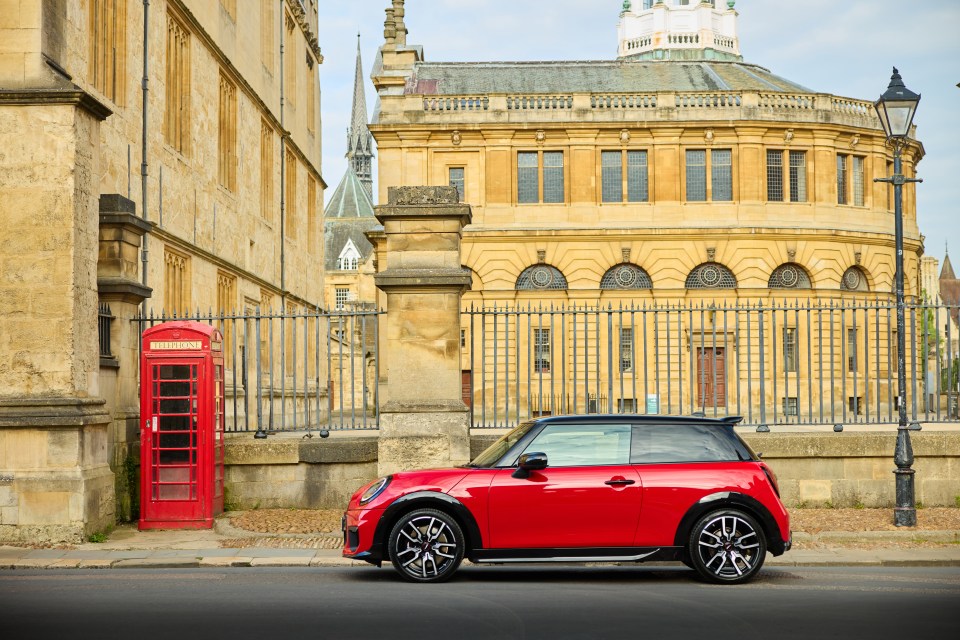 Red MINI Cooper S parked beside a traditional red telephone box in Oxford, with historic university buildings in the background.