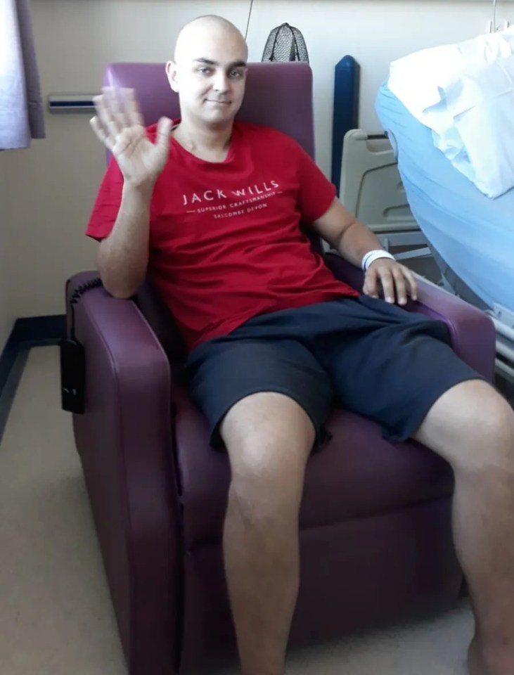 Nick Barnard in a hospital chair, waving.