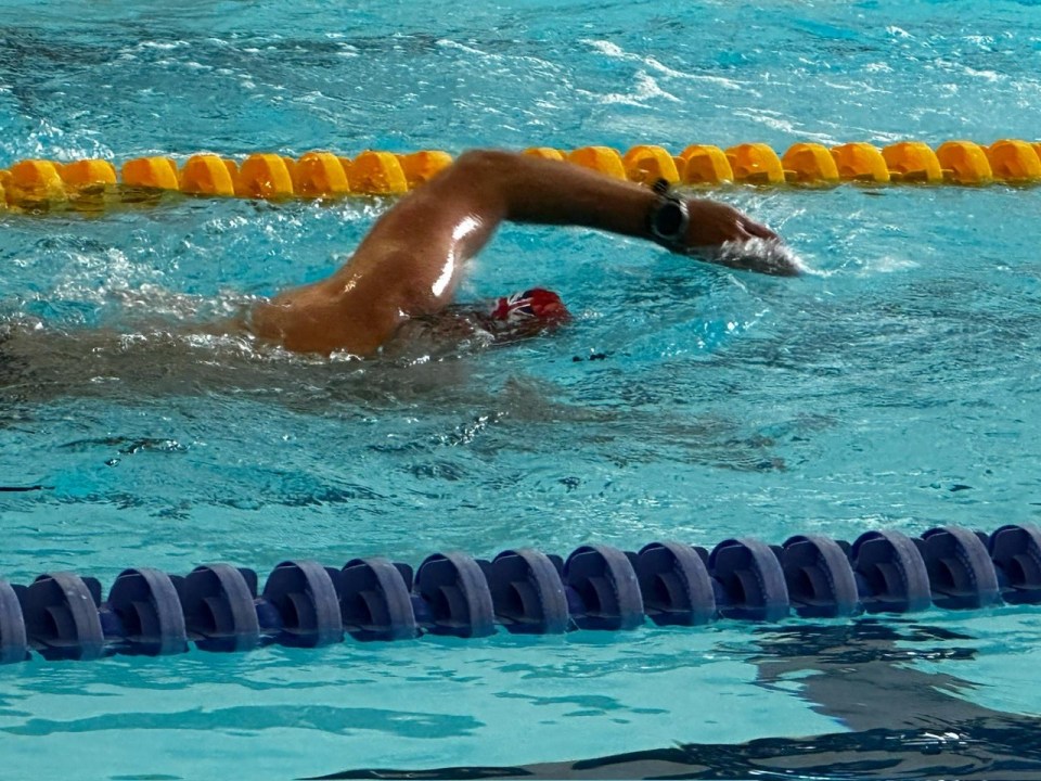 Nick Barnard swimming in a pool, with a red cap visible.